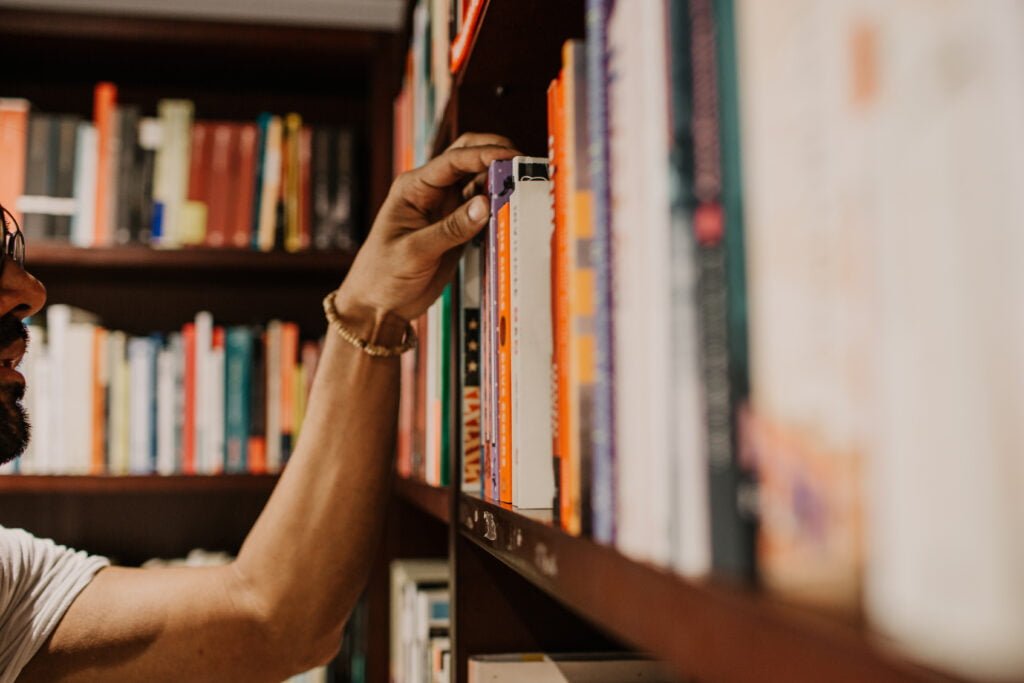 closeup male hand choosing book at library knowle 2022 12 16 10 59 26 utc